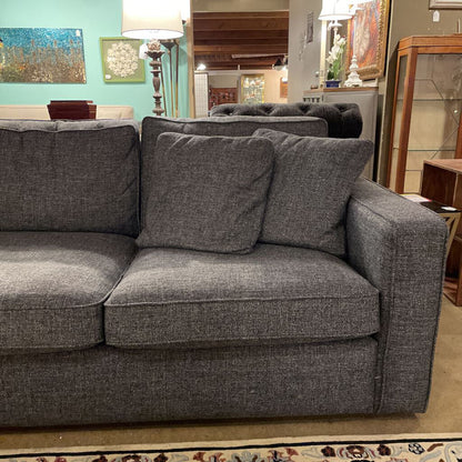 Gray sofa with cushions in a room with furniture and decor.