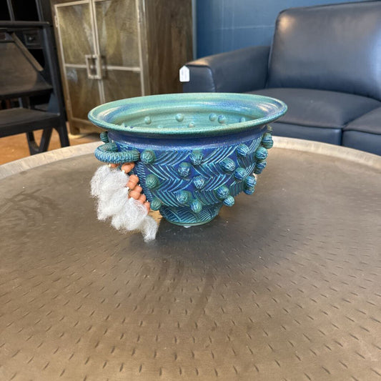 Decorative blue pot with textured design on a round metal table.