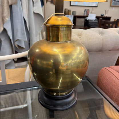 Brass table lamp on a glass surface with a blurred indoor setting