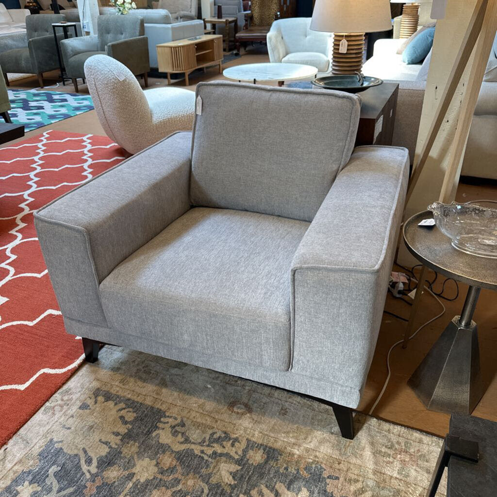 Gray armchair in a room with patterned rugs and furniture
