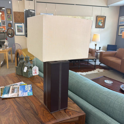 Table lamp with beige shade on a wooden table in a living room setting
