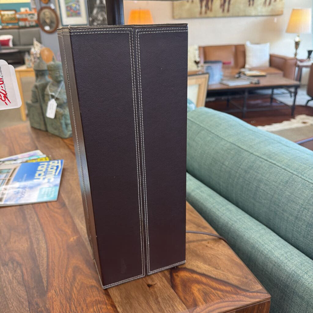 Dark brown leather-bound book on a wooden table with a living room background