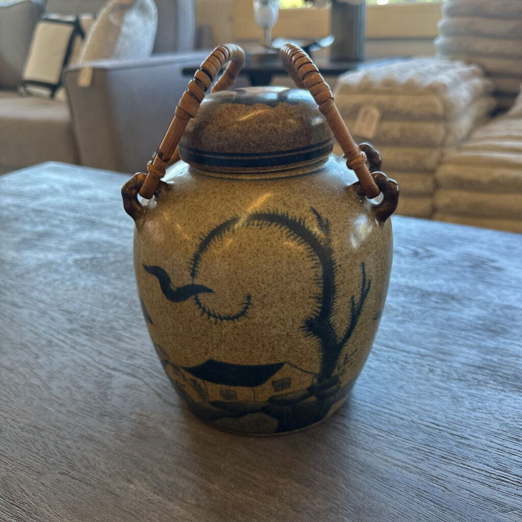 Ceramic jar with handles on a wooden table, with a blurred indoor background