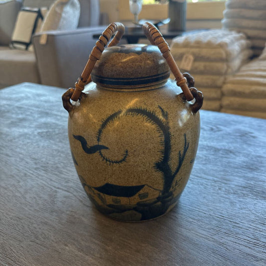 Ceramic jar with handles on a wooden table, with a blurred indoor background
