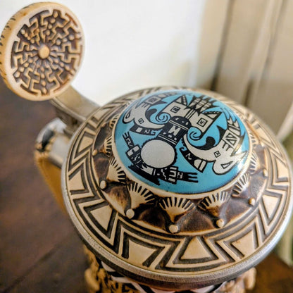 Decorative object with intricate patterns and a blue circular design on a wooden surface.