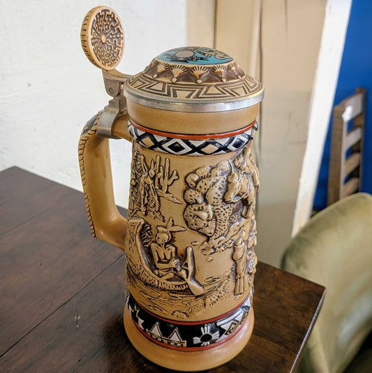 Decorative ceramic beer stein with intricate designs on a wooden table.