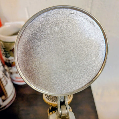 Round metallic object with a textured surface on a stand, blurred background