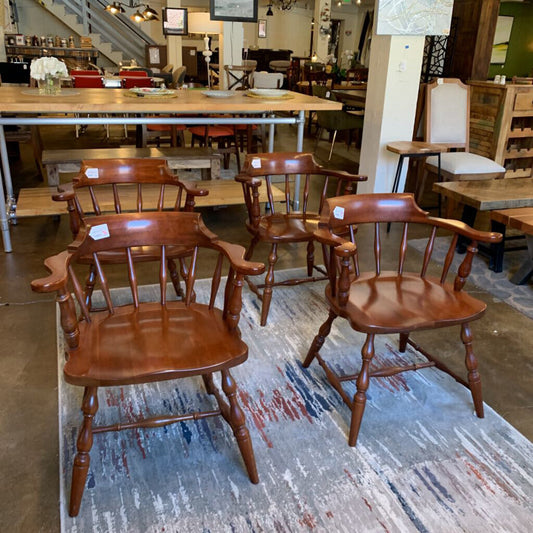 Wooden chairs in a furniture store setting with tables and other chairs in the background.