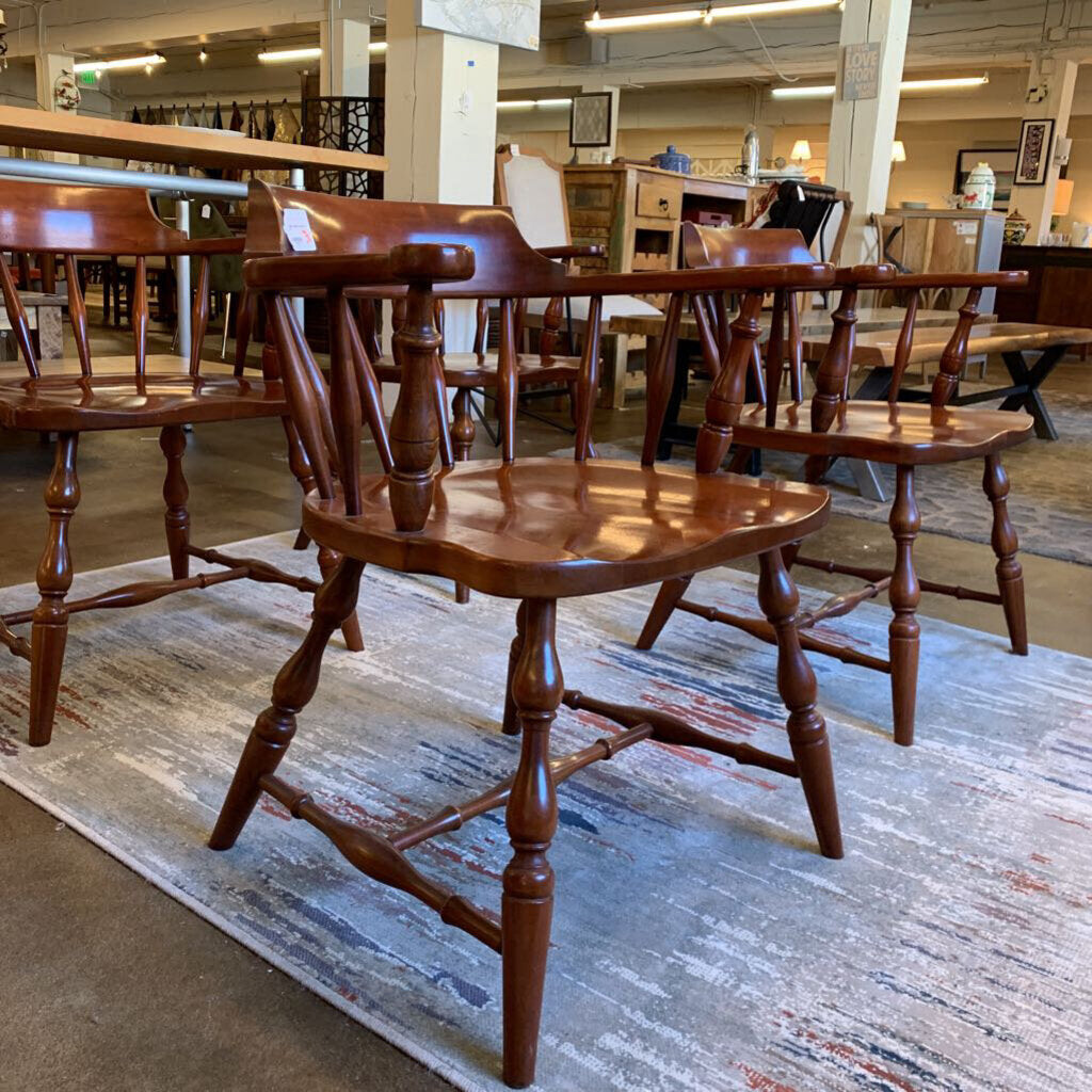 Wooden chairs in a store setting with a rug underneath