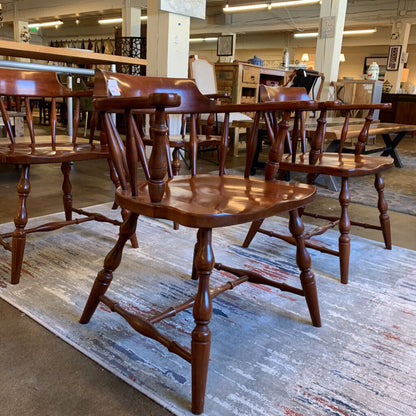 Wooden chairs in a store setting with a rug underneath