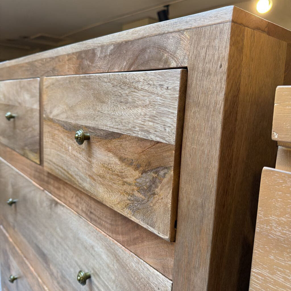 Wooden dresser with multiple drawers and visible grain pattern.