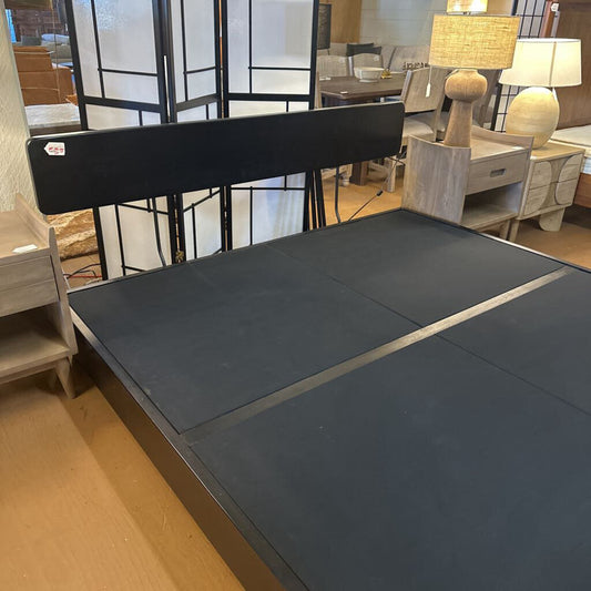 Gray mattress on a bed frame in a room with furniture and decor.