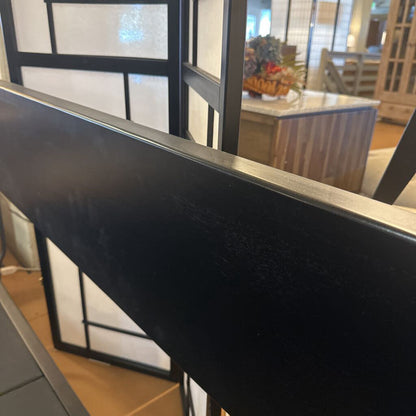 Close-up of a black rectangular object with a blurred indoor setting in the background