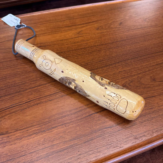 Wooden bat with engraved designs on a wooden surface