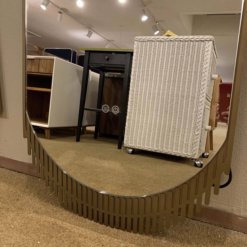 Wicker cart on wheels inside a store with a curved metal barrier.