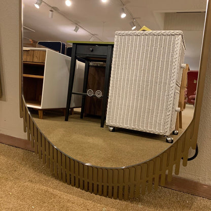 Wicker cart on wheels inside a store with a curved metal barrier.