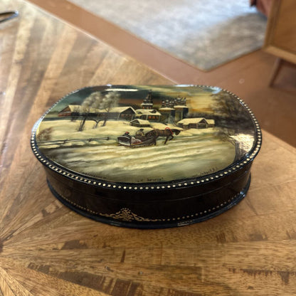 Decorative box with a painted scene on a wooden surface