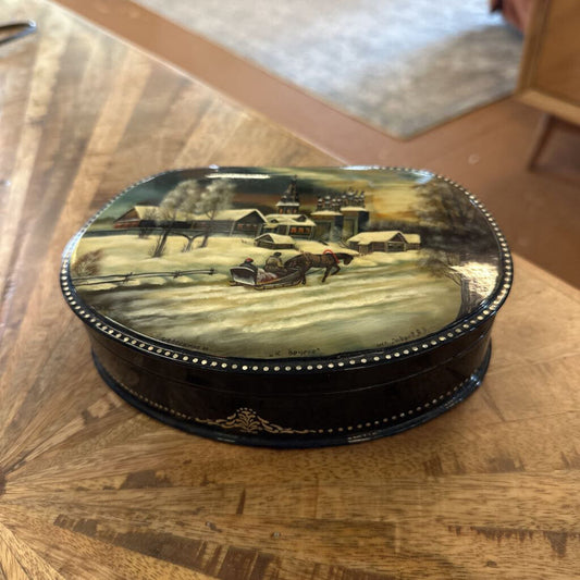 Decorative box with a painted scene on a wooden surface