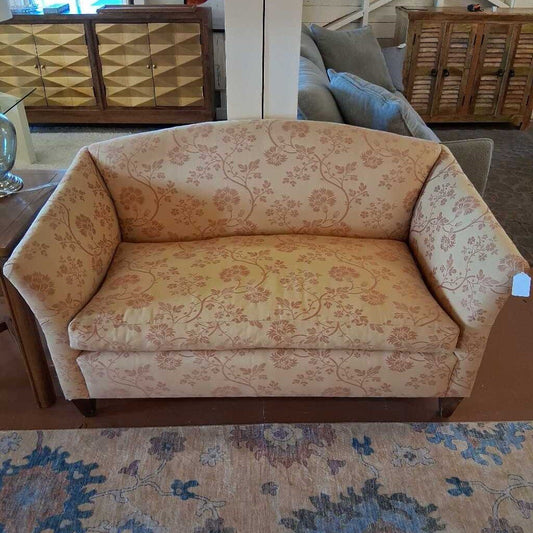 Floral-patterned sofa in a room with wooden furniture and a rug.