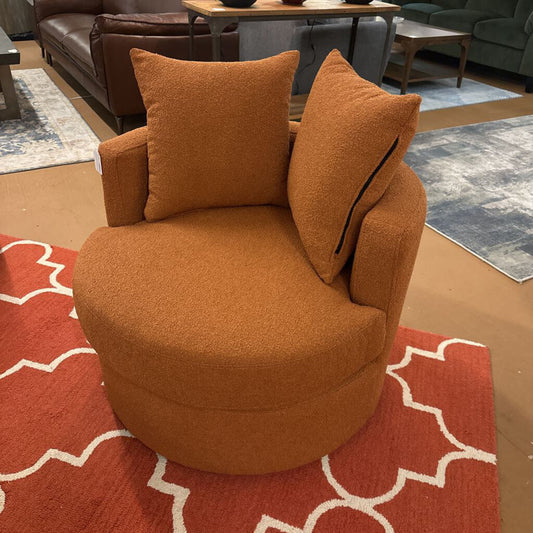 Orange armchair with cushions on a red patterned rug in a living room setting.