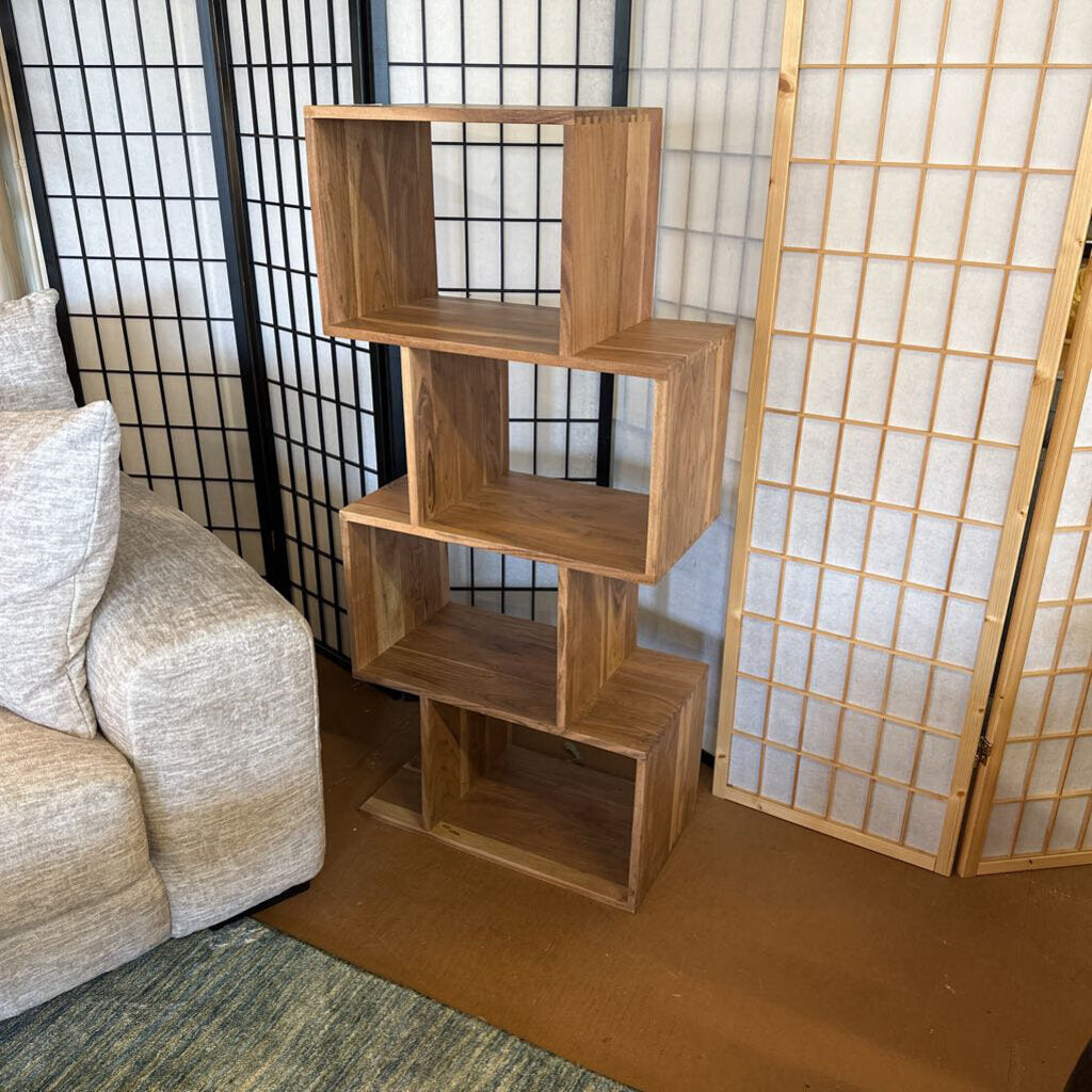 Wooden bookshelf against a wall with a sofa and shoji screens in the background