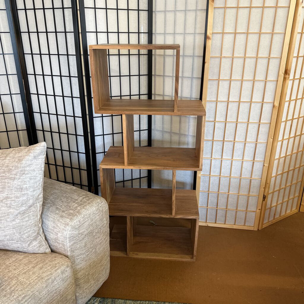 Wooden bookshelf against a room divider with a couch on the left.