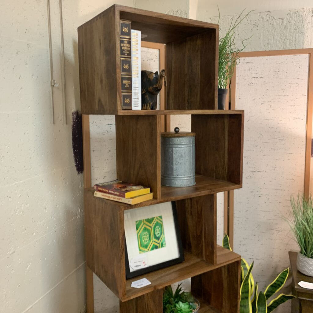 Wooden bookshelf with books and decorative items against a light brick wall.