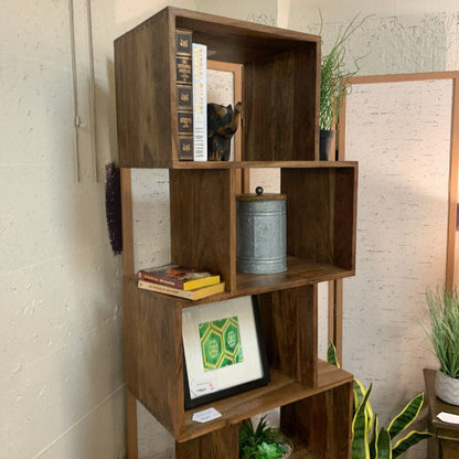 Wooden bookshelf with books and decorative items against a light brick wall.