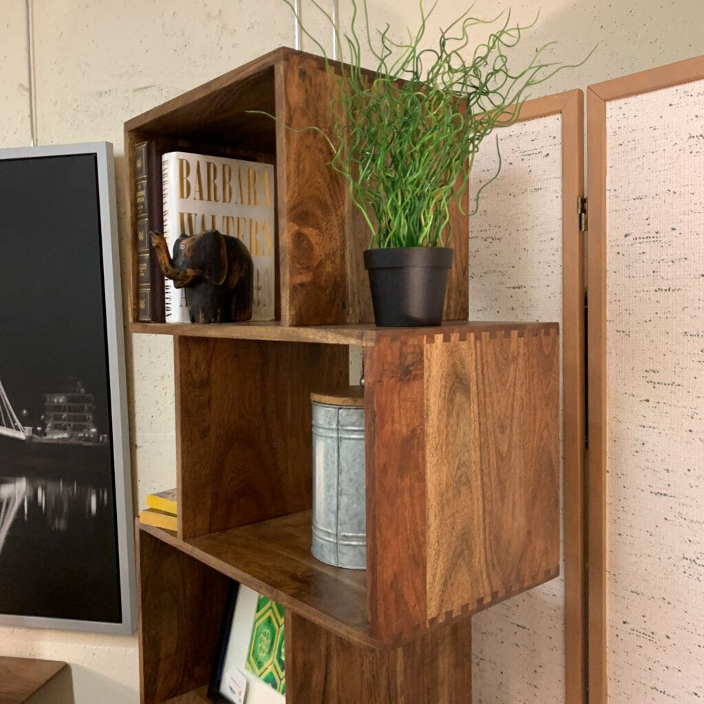 Wooden shelf with decorative items including a plant, books, and a small statue.