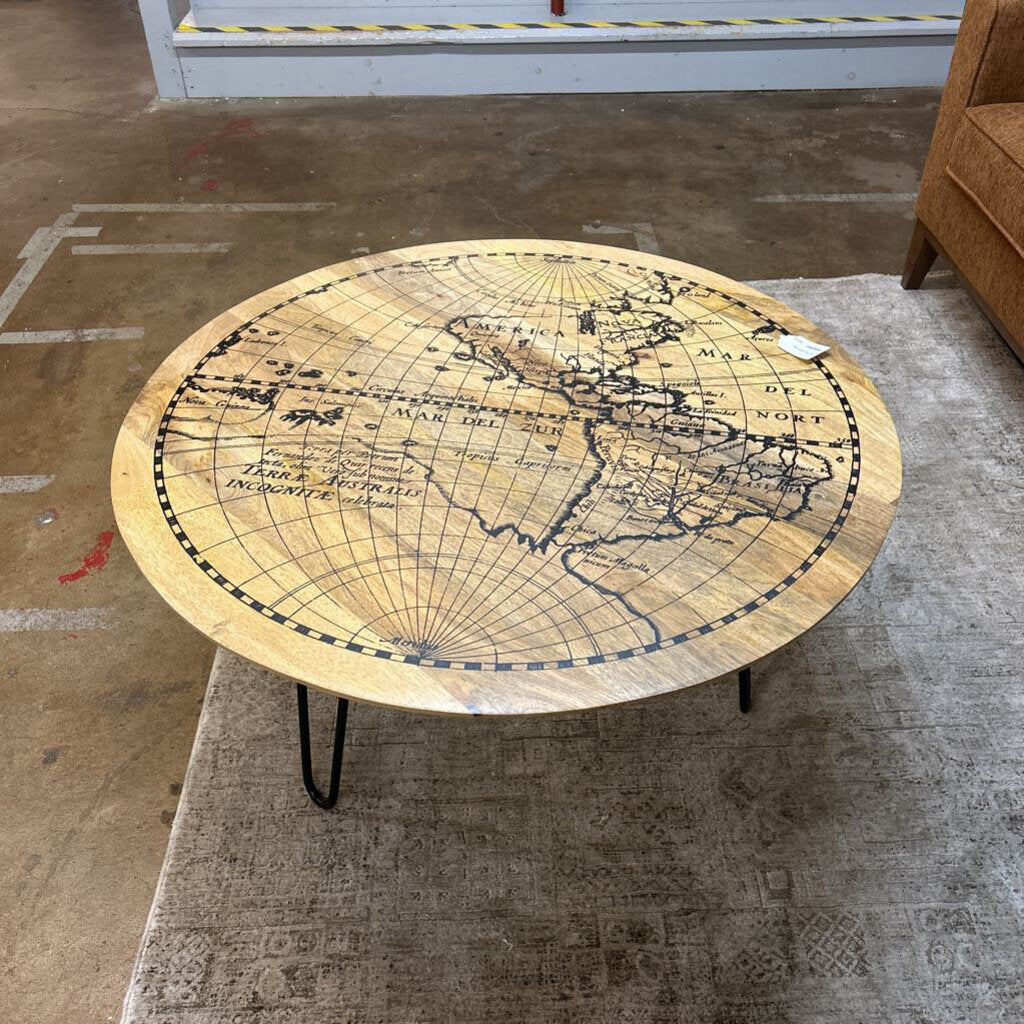 Round coffee table with world map design on a textured floor.