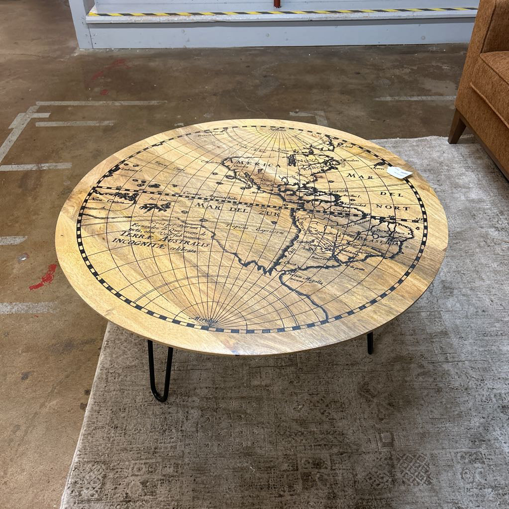 Round coffee table with world map design on a textured floor.
