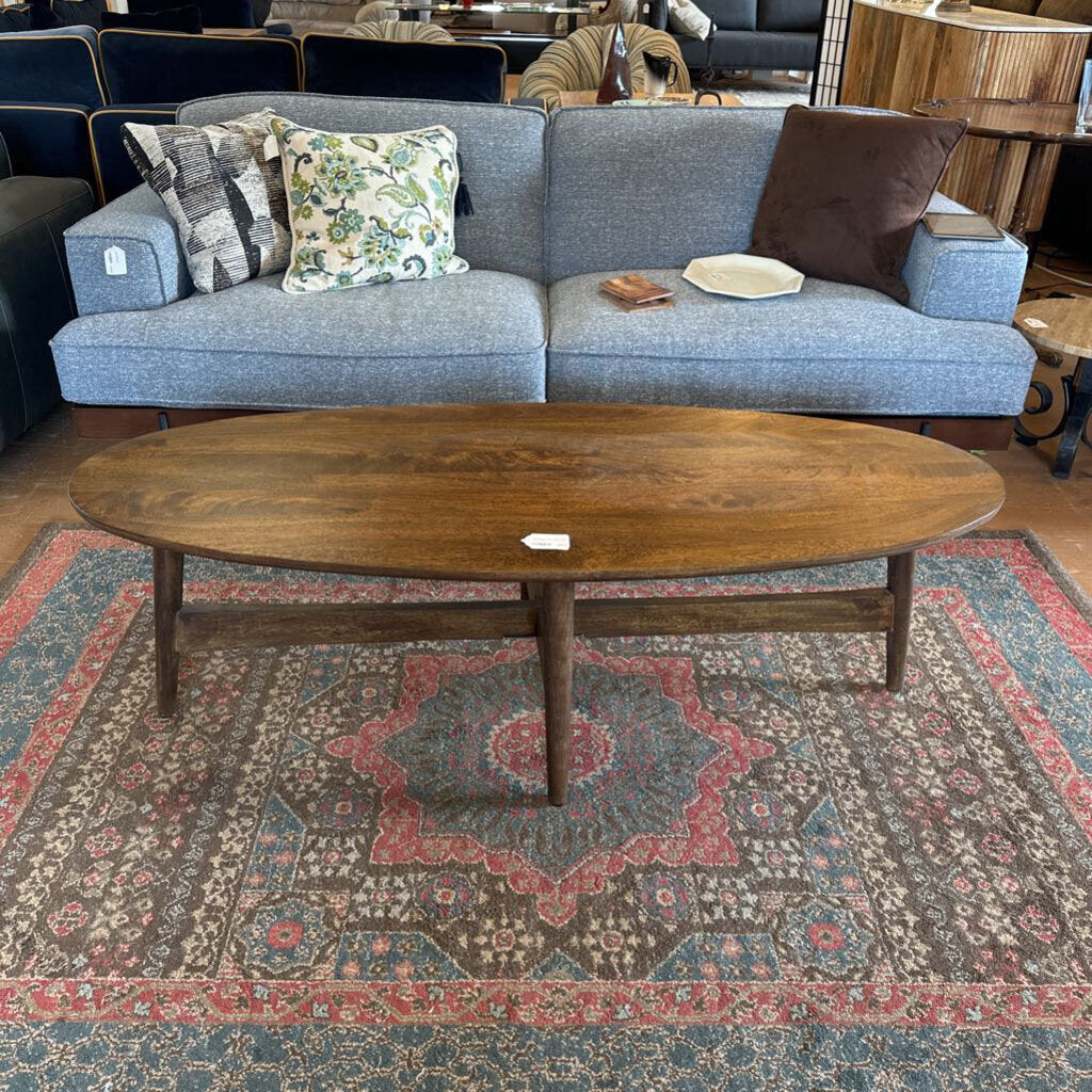 Blue sofa with patterned cushions and a wooden coffee table on a decorative rug.