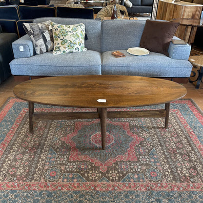 Blue sofa with patterned cushions and a wooden coffee table on a decorative rug.