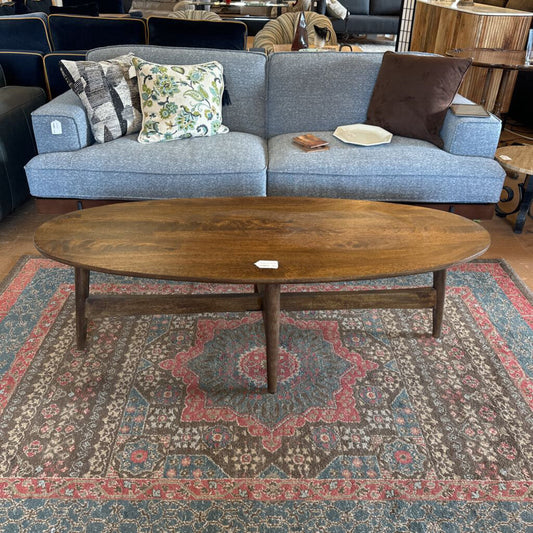 Blue sofa with patterned cushions and a wooden coffee table on a decorative rug.