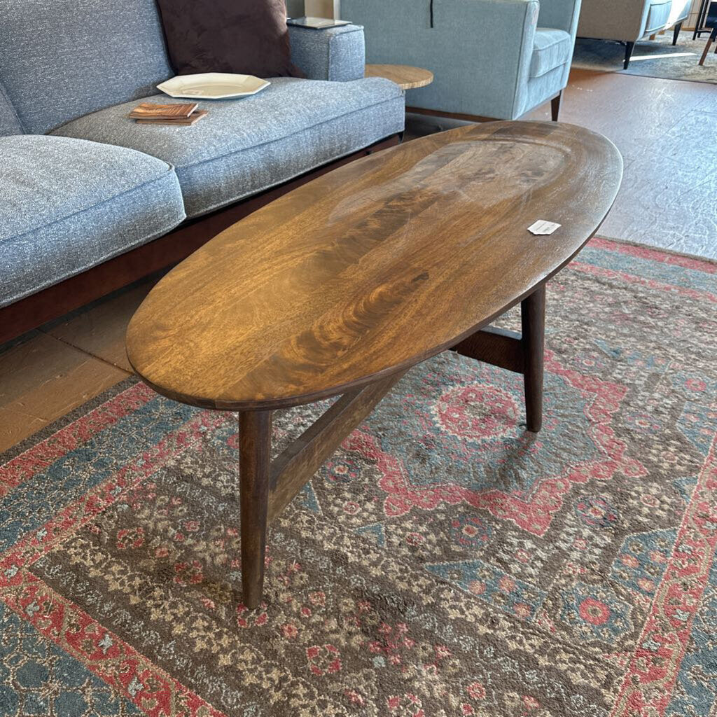 Wooden coffee table in a living room setting with a patterned rug and sofa.