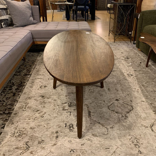 Wooden coffee table in a living room setting with a sectional sofa and rug.