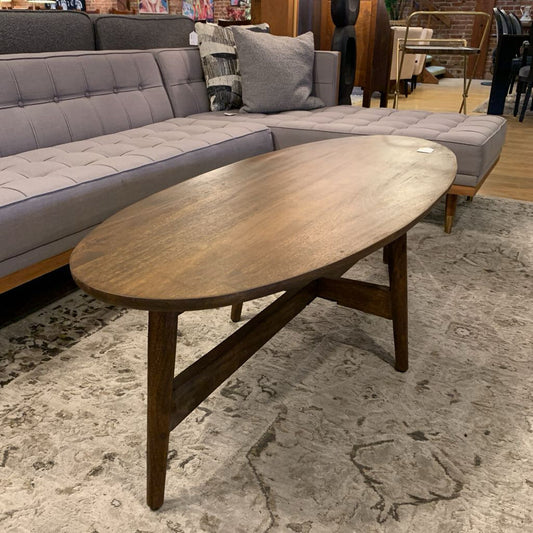 Wooden coffee table in a room with a gray sectional sofa and rug.