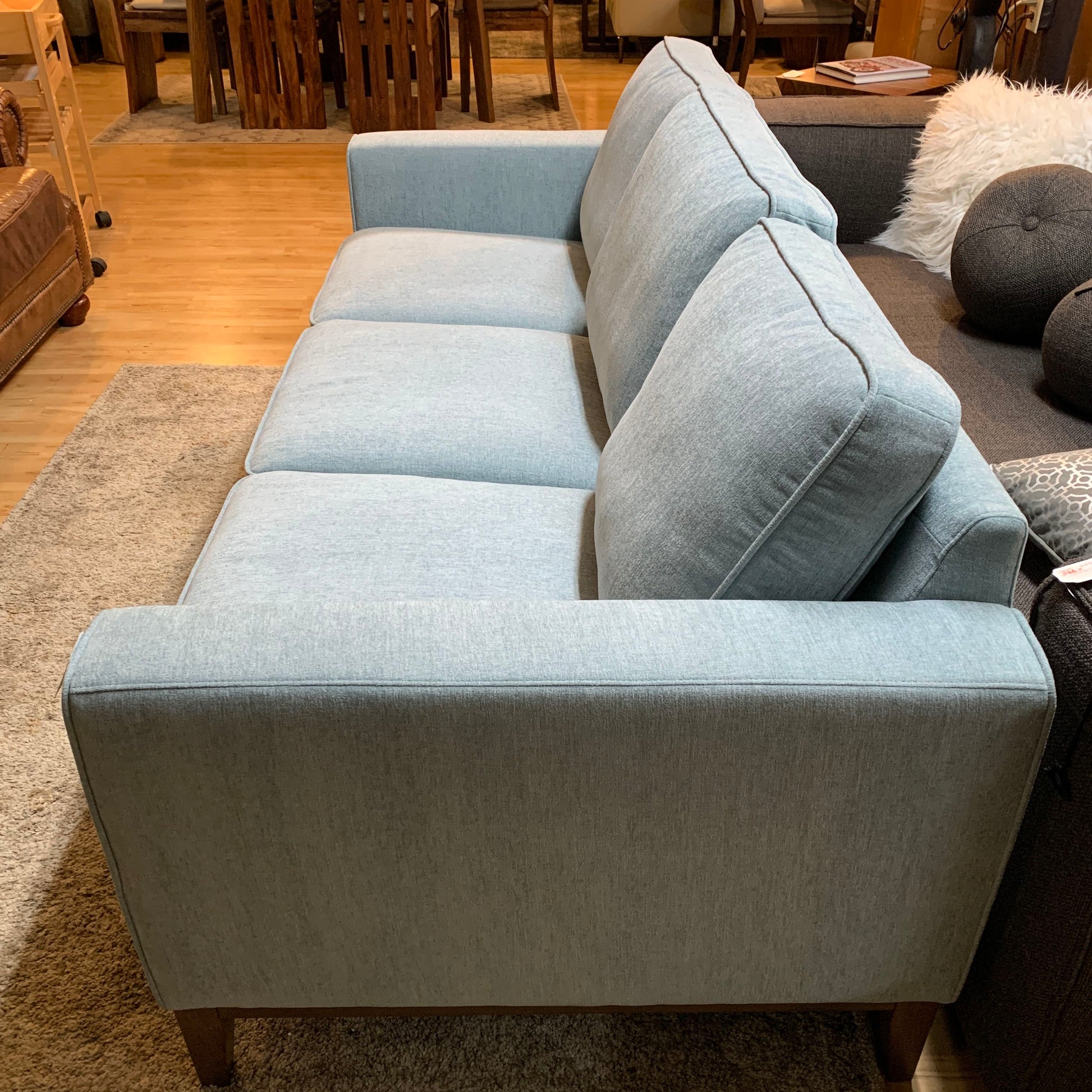 Light blue sofa in a room with wooden flooring and furniture.