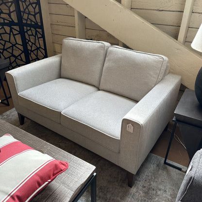 Beige sofa in a living room setting with a staircase in the background