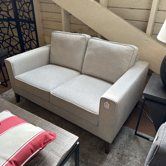 Beige sofa in a living room setting with a staircase in the background