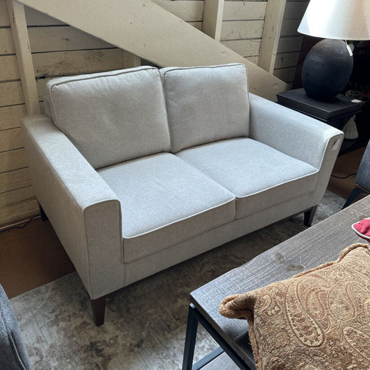 Light gray sofa in a room with wooden walls and a lamp.