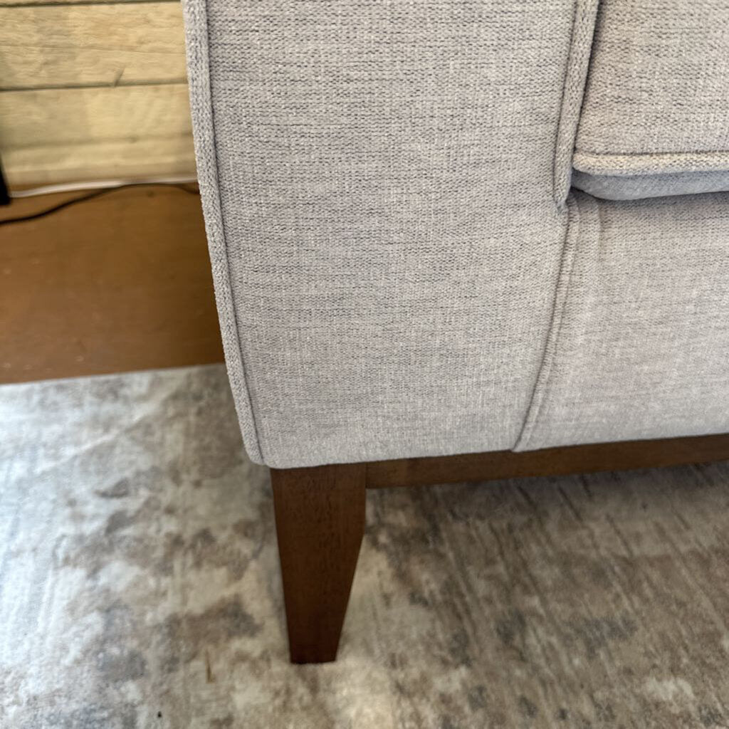 Gray upholstered chair with wooden legs on a patterned rug