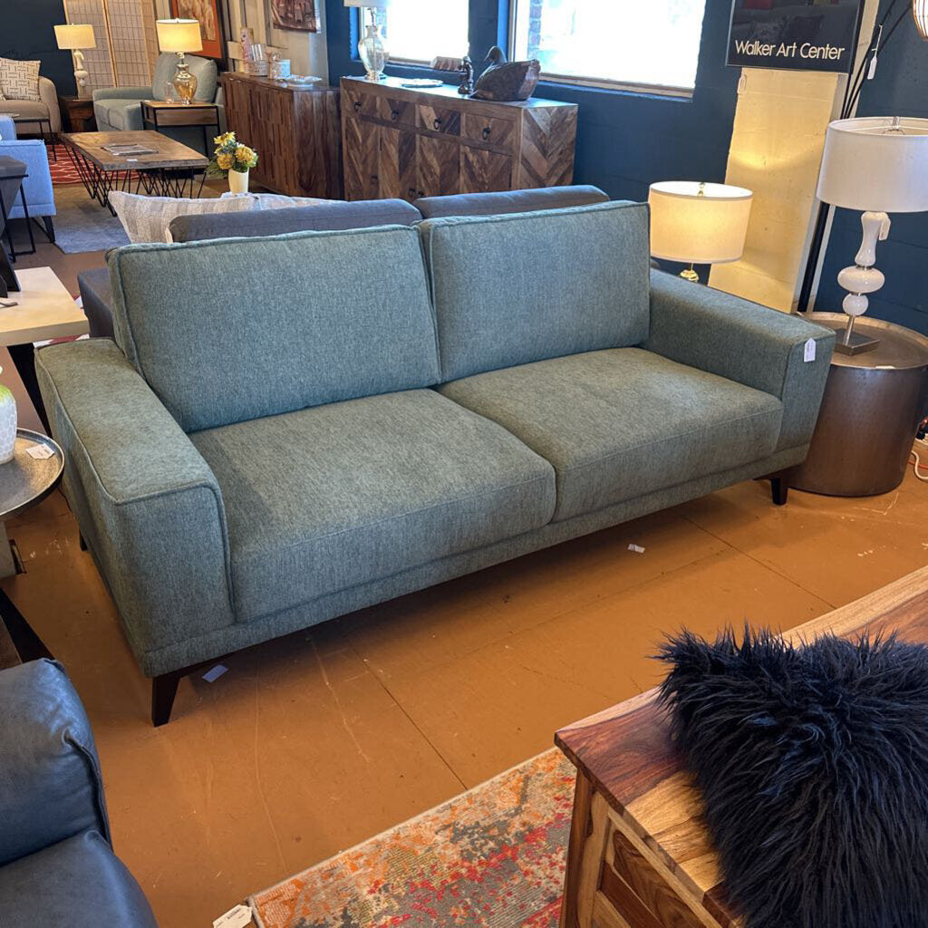 Blue sofa in a showroom with various furniture and decor items.