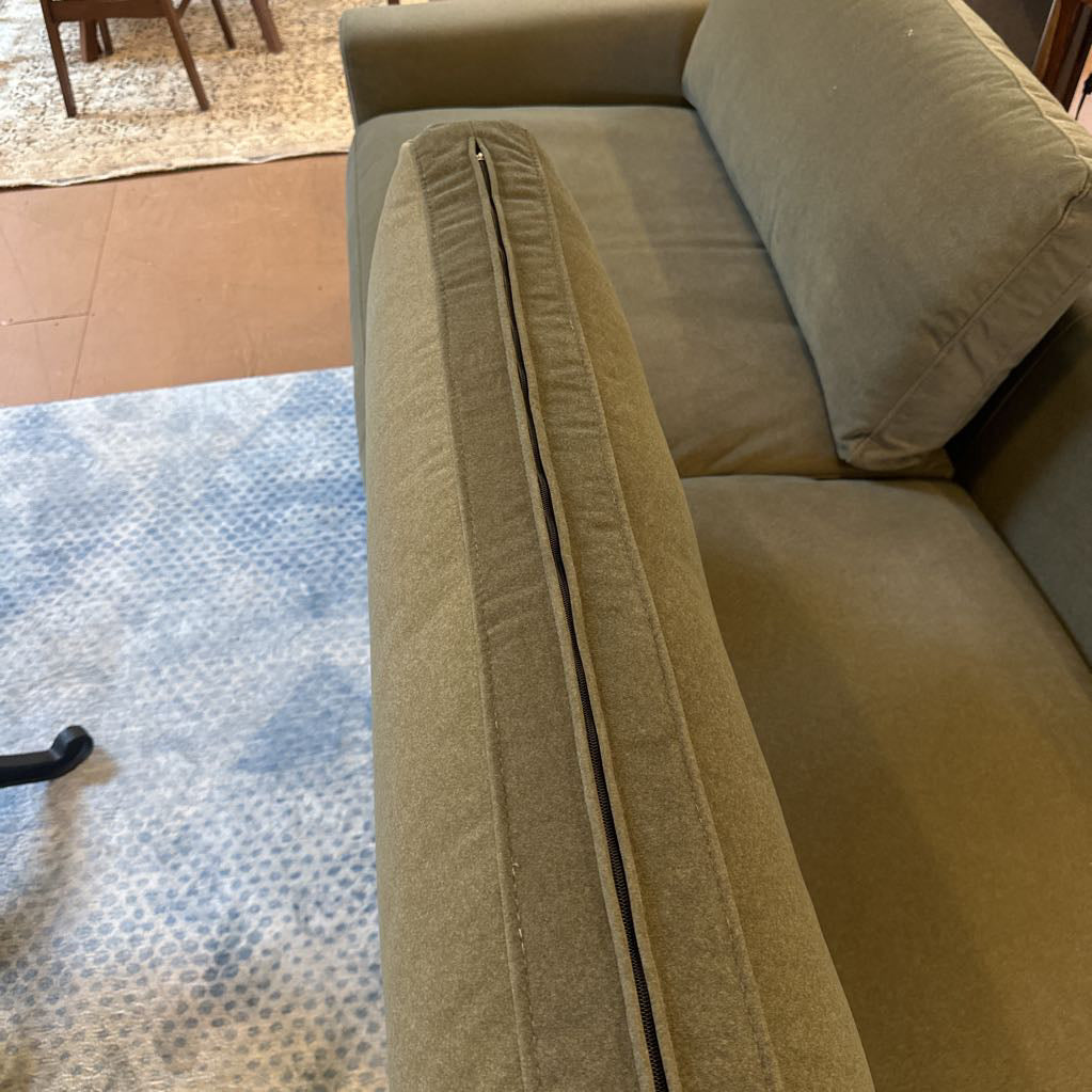 Brown sofa with a visible seam on a patterned rug