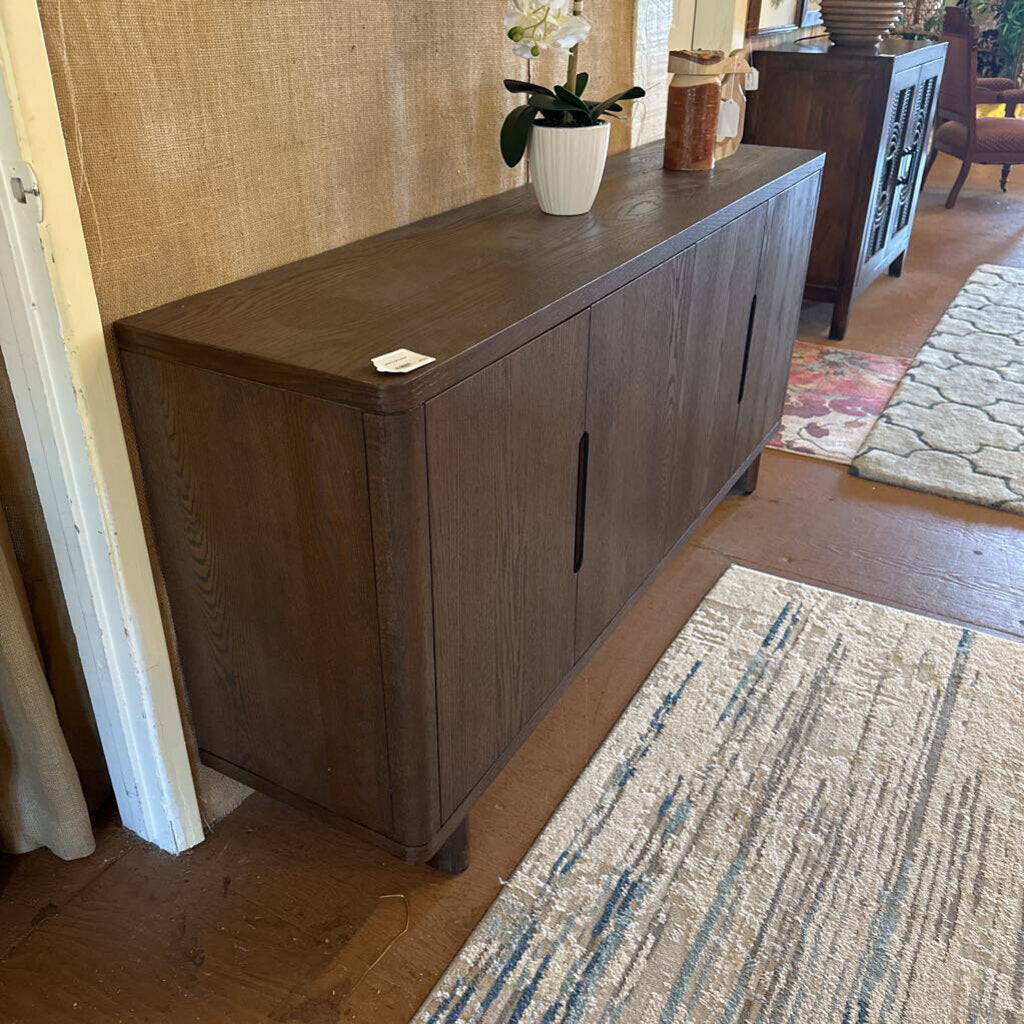 Wooden sideboard in a room with a textured wall and rug.