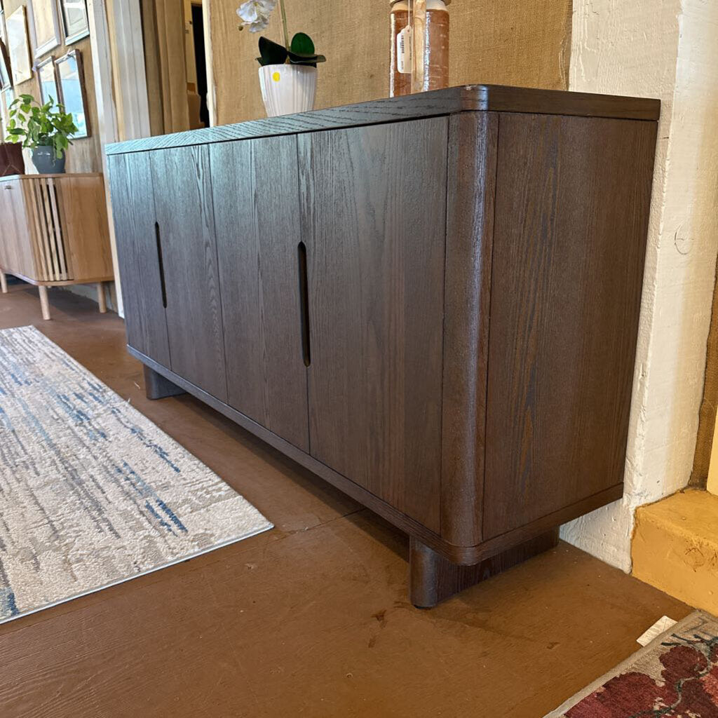 Dark wood sideboard in a room with a rug and decorative items.