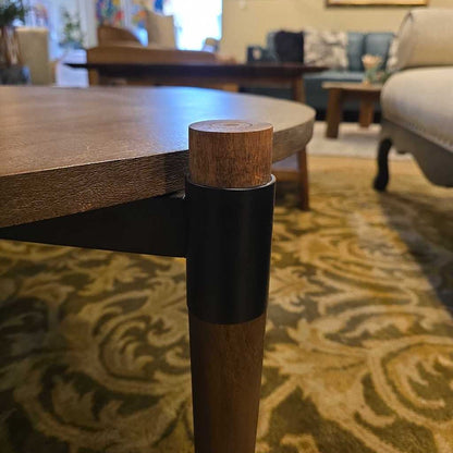 Close-up of a wooden table leg with a blurred living room background