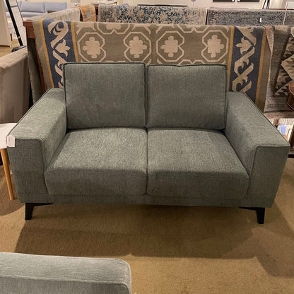 Gray sofa in a store setting with patterned rug in the background