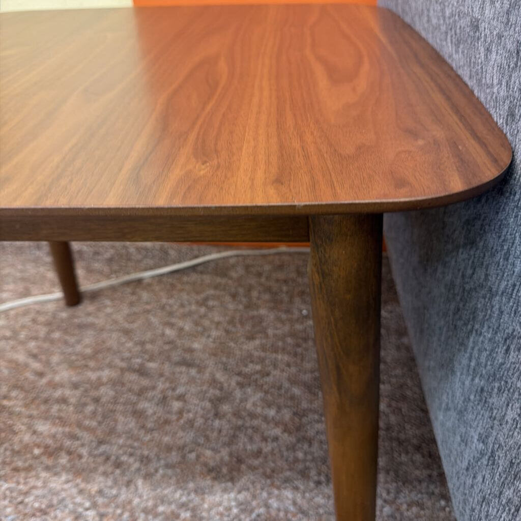 Wooden table corner with a gray sofa and carpeted floor