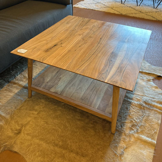 Wooden coffee table in a living room setting with a rug and sofa.